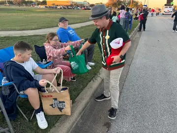 Jonathan Coffman handing a bag to children along a holiday parade route