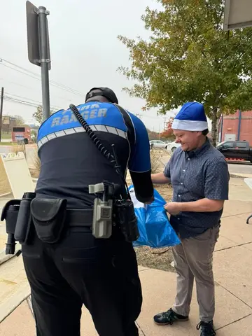 Jonathan Coffman handing a Blue Santa gift bag to a public safety officer