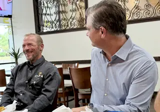 Dr. Quintin Shepherd and Mayor Doug Weiss seated at a table, smiling during a conversation.