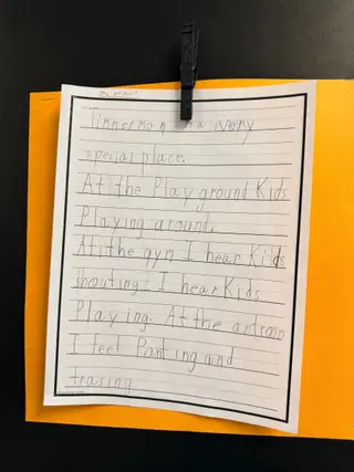 Student writing on display describing Timmerman as a special place, with playground, gym, and art room activities