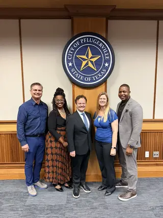 Jonathan Coffman with Pflugerville council colleagues in front of the City of Pflugerville seal